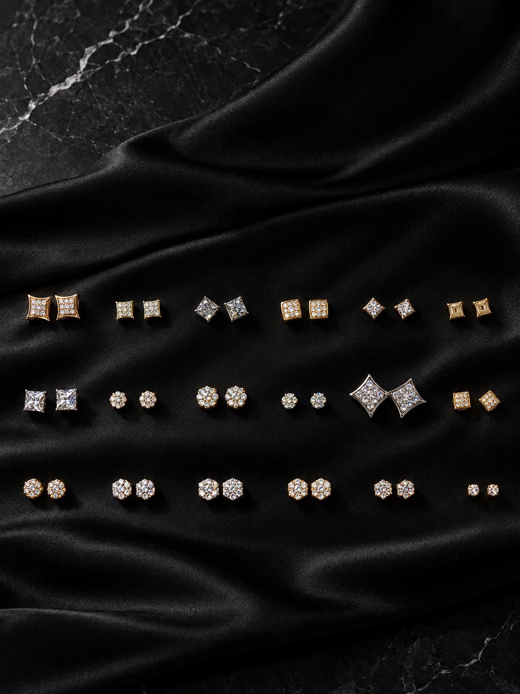 Pares de aretes de oro y piedras claras en tres filas, sobre satén negro.
