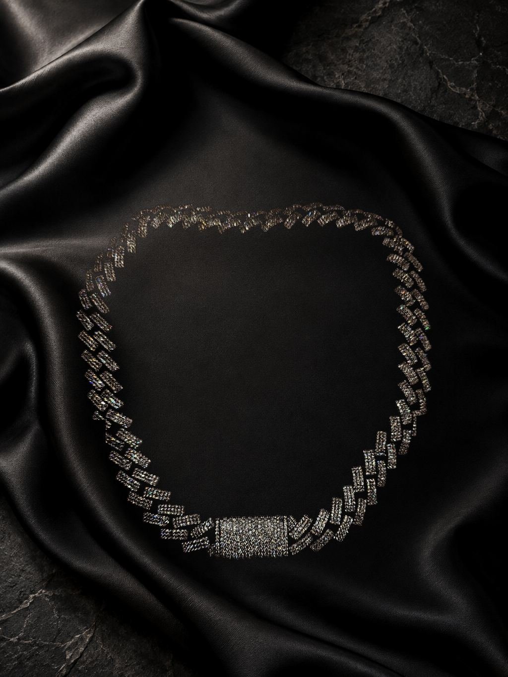 Silver-tone Cuban chain set with clear stones, box clasp with pavé, on black satin.